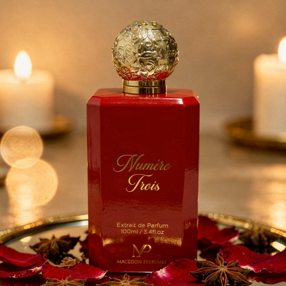 Red perfume bottle with gold cap on a decorative tray with candles in the background